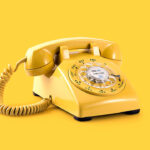 Yellow rotary phone on yellow background