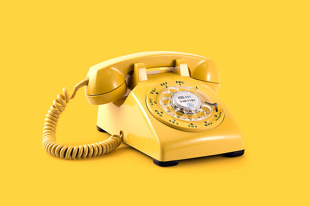 Yellow rotary phone on yellow background